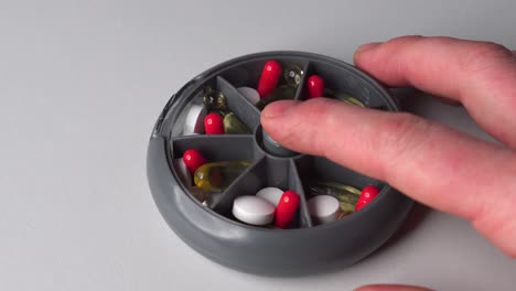 person push plastic medicine container button and change sections, pills inside