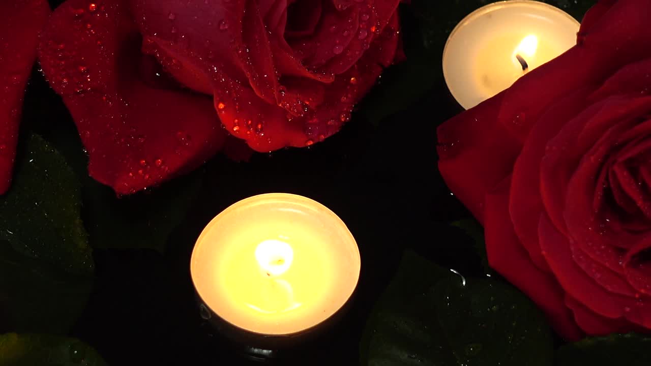 Rosen und Kerzen auf schwarzem Hintergrund