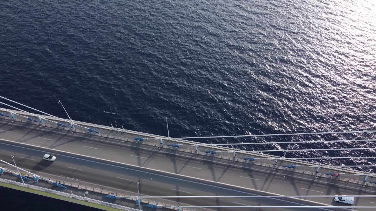 Aerial view of cars passing over a suspended bridge at sunset, Antirion bridge, Corinthian straight, Greece.