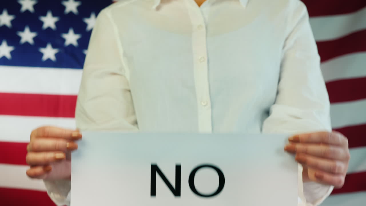 여자는 미국 국기 배경에 더 이상 없다는 포스터를 들고