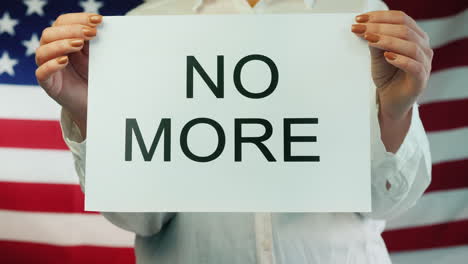 Woman-Holds-Poster-Stating-No-More-On-American-Flag-Background