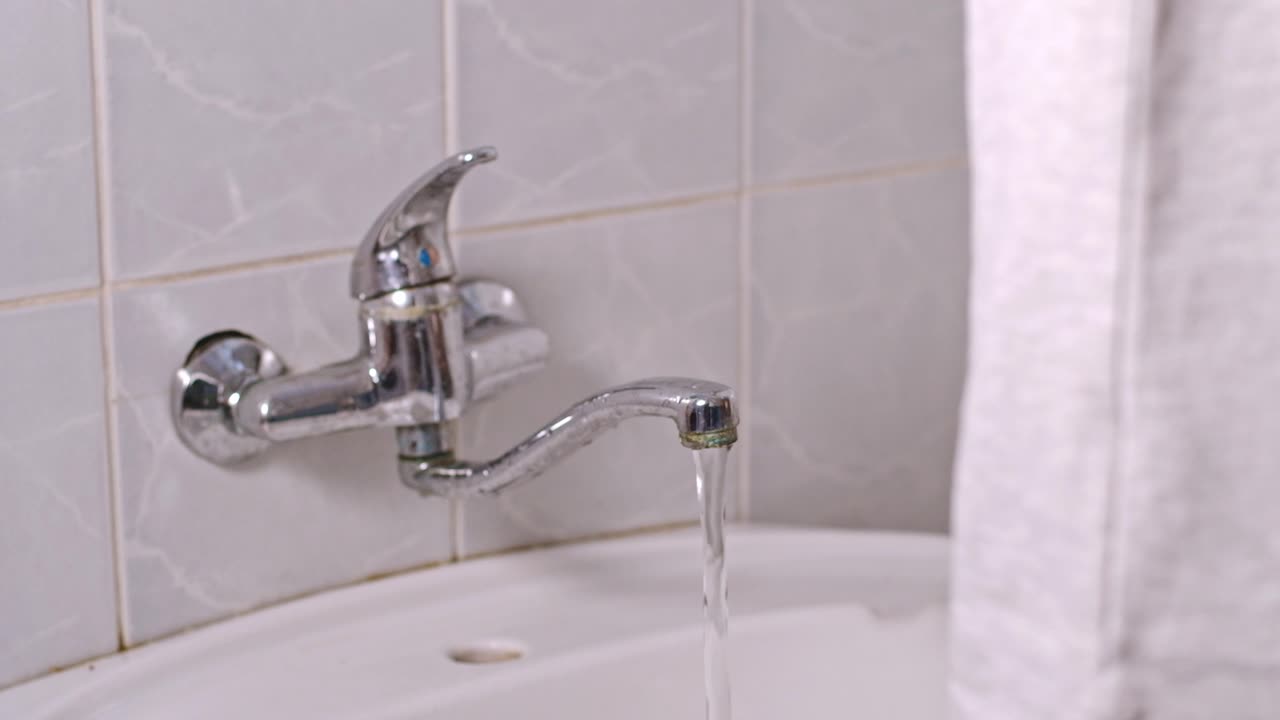 Primer plano de un joven echando pasta de dientes en el cepillo de dientes en el baño. Rutina matutina.