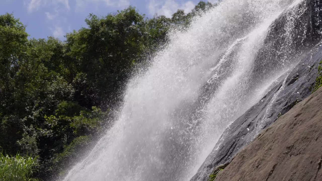 aguas que fluyen rápidamente en cámara lenta a través de la superficie rocosa con vistas a los exuberantes árboles verdes de la jungla en el fondo