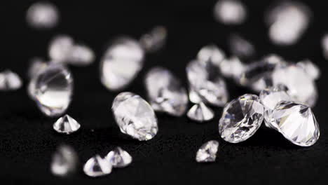 toma cinematográfica en cámara lenta de diamantes reales de varios tamaños cayendo sobre la mesa negra para ser examinada en una joyería