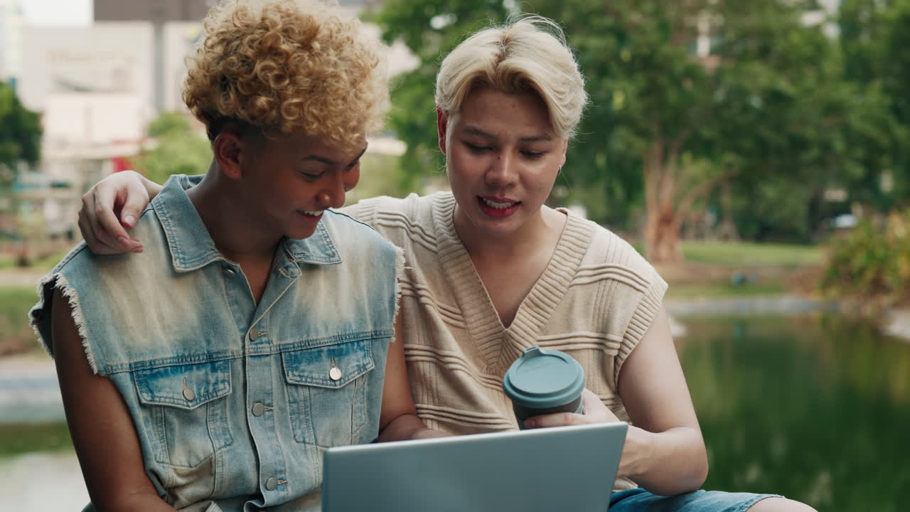 Two friends using a laptop in the park