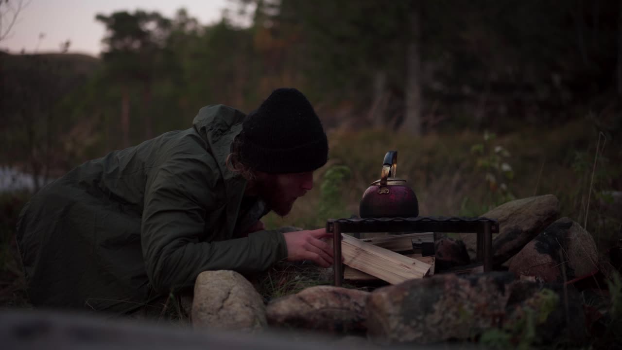 Man Blowing Air On Firewood To Burn Easily