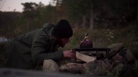 man blowing air on firewood to burn easily