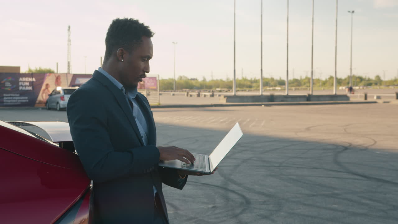 Businessman working on a laptop in a parking lot