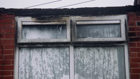 fire damaged home in blackburn, uk with blacked windows