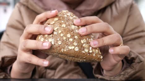 person holding a loaf of multigrain bread