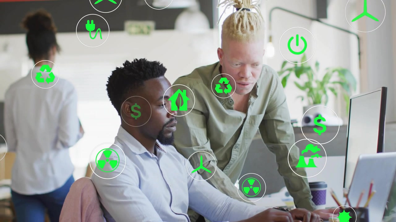 Peer pointing at screen, seated man pausing typing and analyzing finance with green overlay icons