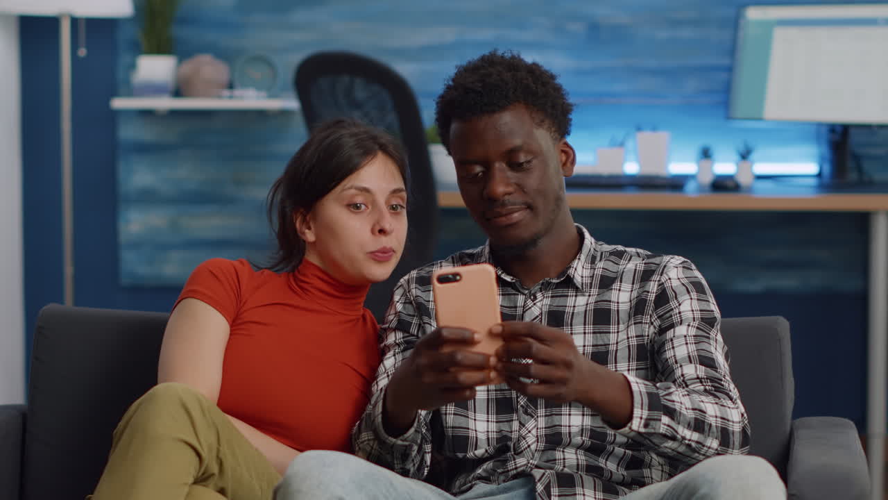 Joyful interracial couple taking selfies with smartphone