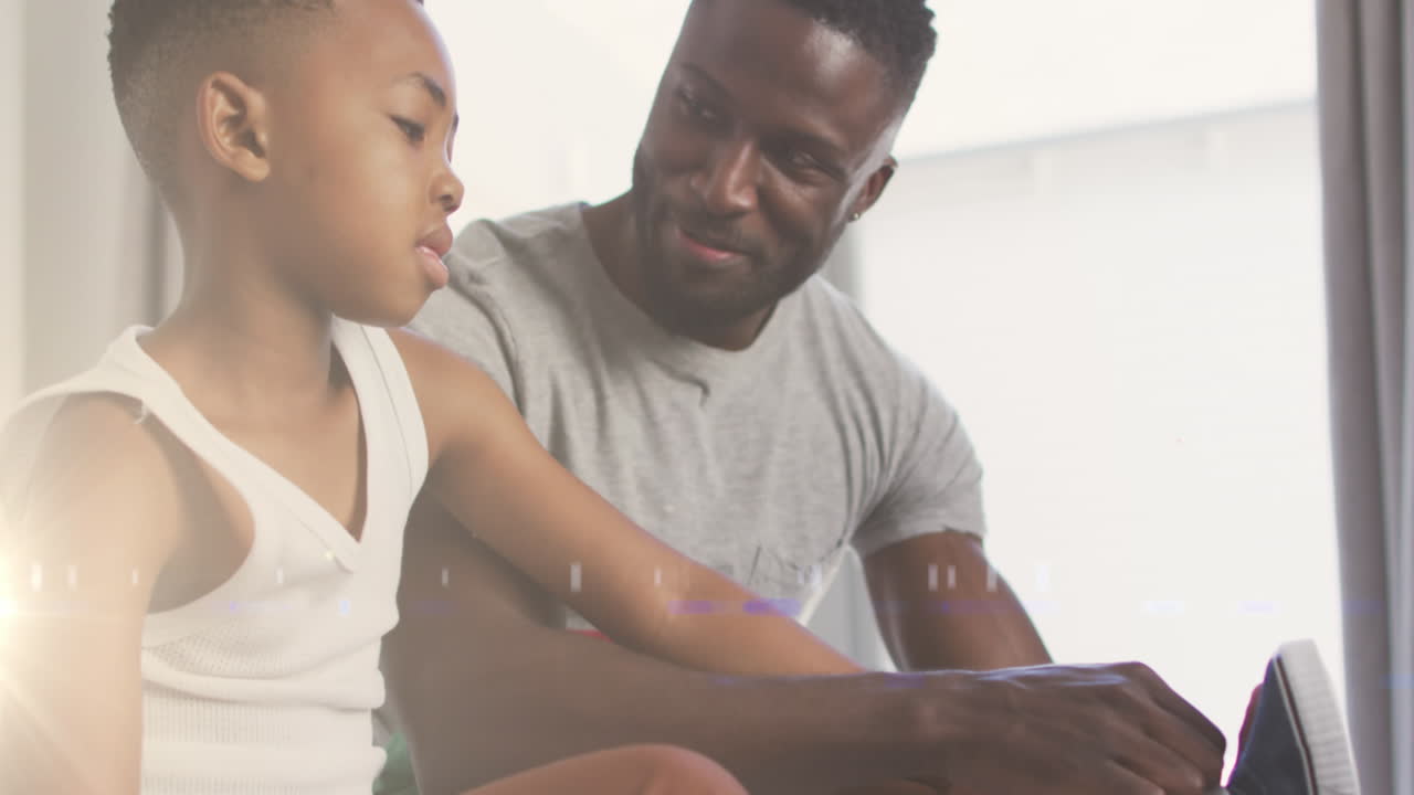 Animation of lights over happy african american father helping son to tie shoe