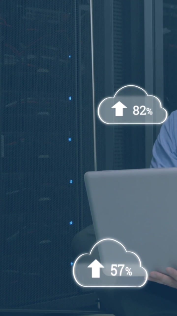 Animation of clouds with numbers over stressed caucasian man working on laptop in server room