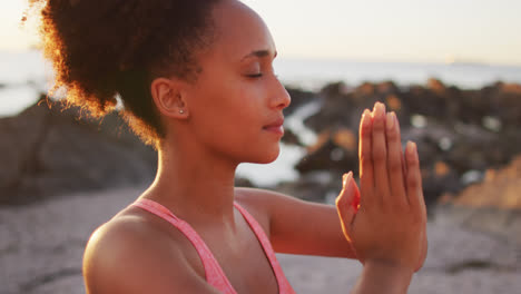 close up view of african american woman practicing yoga and meditating on the rocks near the sea