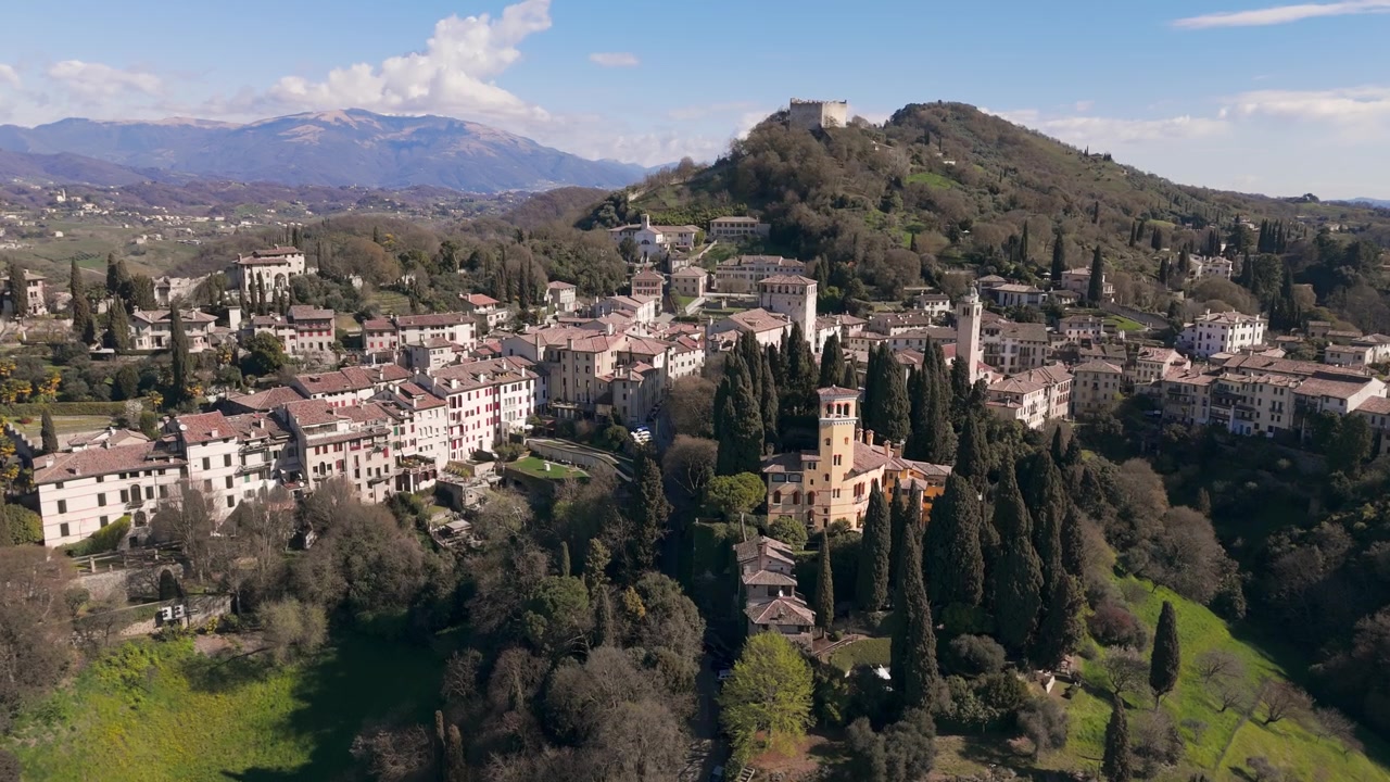 Panoramica aerea della storica città di Asolo annidata tra le colline e una vegetazione lussureggiante.