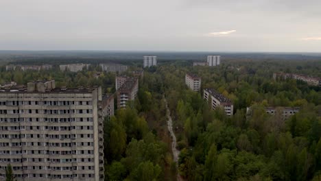 vista aérea de una calle vacía rodeada de edificios y árboles abandonados en pripyat, ucrania durante el otoño - desastre de chernobyl - disparo de drones
