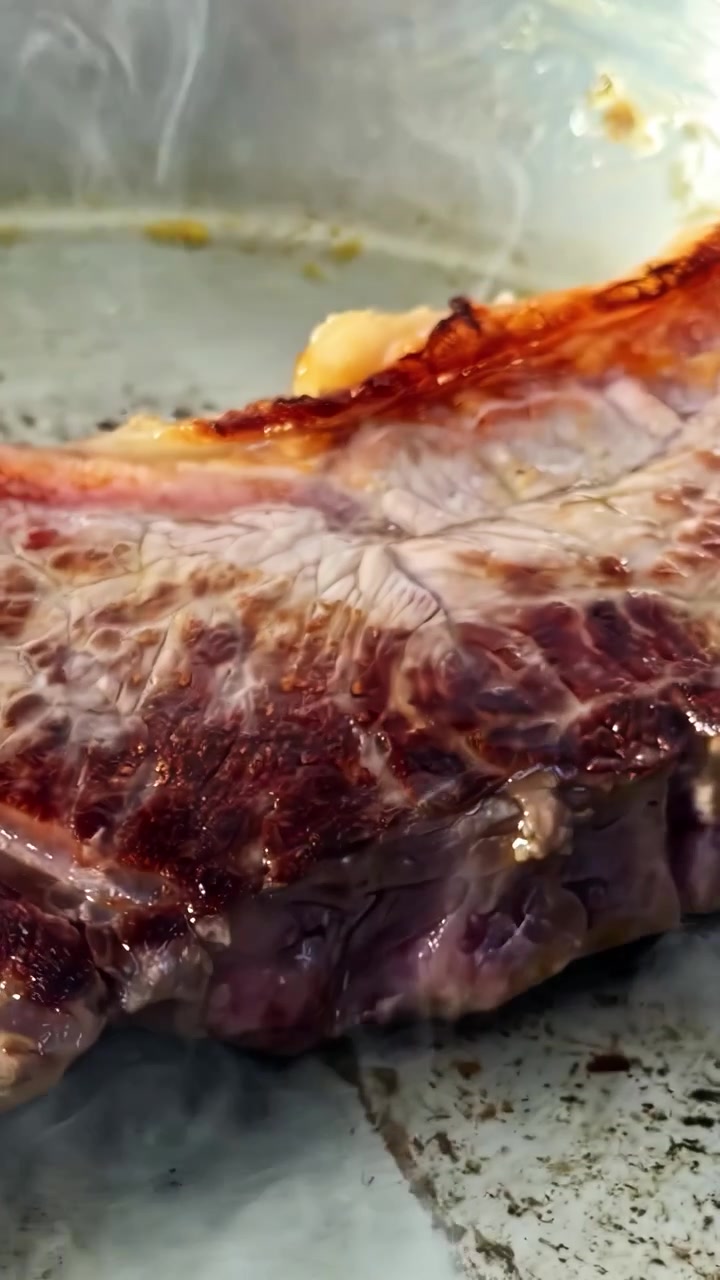Spatola nera che preme carne con pelle su una piastra calda con crosta dorata che si forma sui bordi, primo piano estremo.