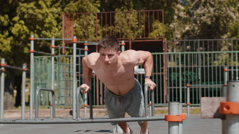 Athletic bodybuilder shirtless muscular man doing sport workout pushup exercise on parallel bars