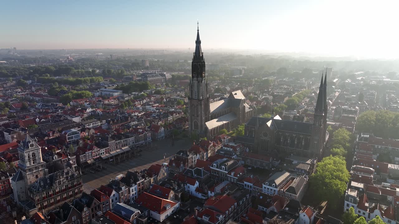 Vista aerea semi-orbitale della Nieuwe Kerk e dei tetti rossi circostanti a Delft, Paesi Bassi, durante la luce dorata del mattino