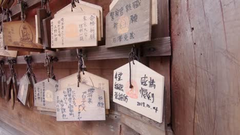 japanese ema hanging at a shrine with prayers or wishes of religious people written on them