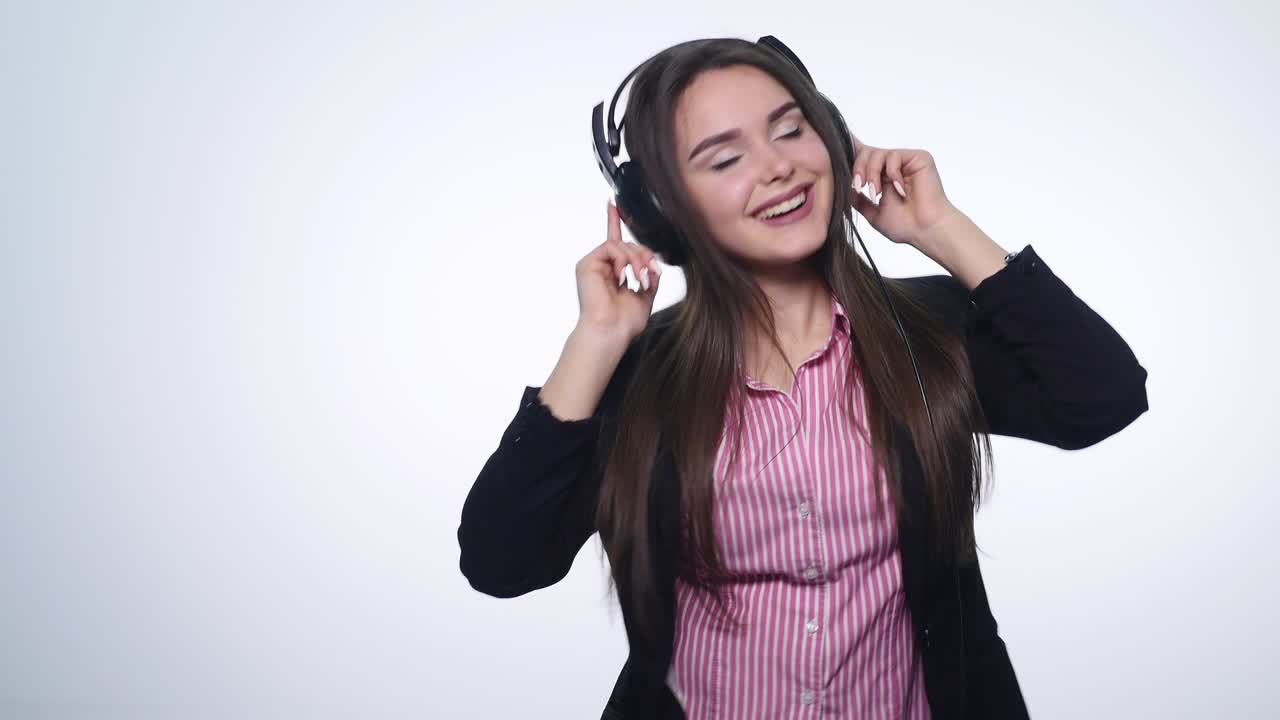 웃는 행복한 젊은 여성이 헤드폰으로 음악을 듣고 색 배경에 고립된 춤을 추고 있습니다.