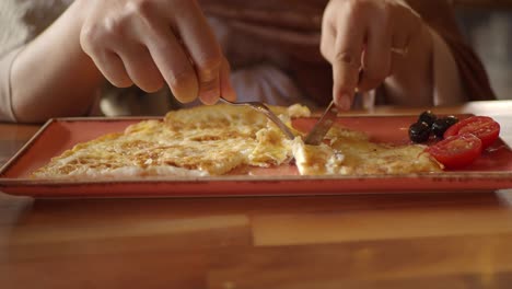 persona comiendo huevos revueltos con tomates y aceitunas
