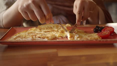 person eating scrambled eggs with tomatoes and olives