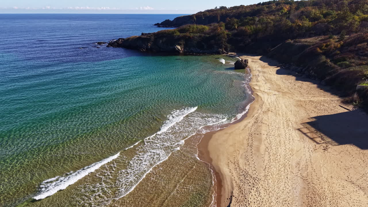 Spiaggia soleggiata con onde delicate e cielo azzurro sconfinato che si affaccia su acque calme in una serena località costiera durante il mezzogiorno