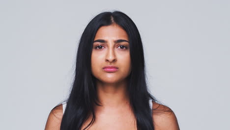 head and shoulders studio shot of woman looking at camera with serious expression in slow motion