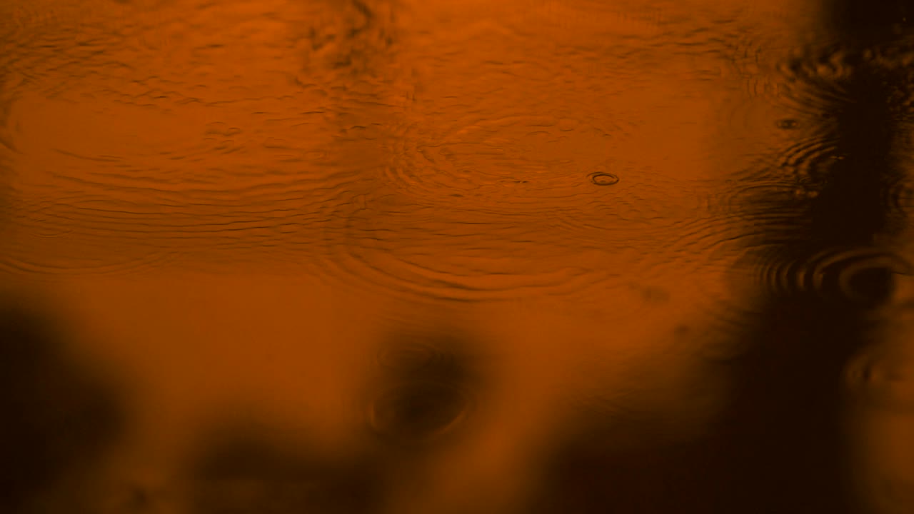 agua en movimiento lento gotas de lluvia cayendo sobre el agua sobre el suelo, hermosa superficie azul onda papel tapiz abstracto, patrón de círculo en el suelo, salpicaduras de gota de lluvia caendo y goteando en el suelo mojado