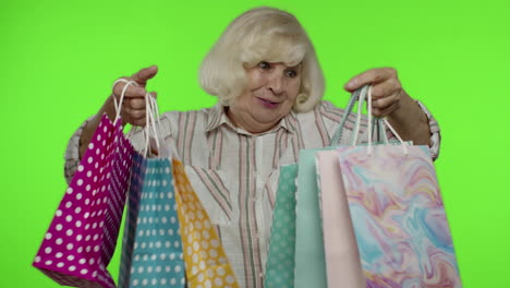 abuela sosteniendo bolsas de compras, regocijándose de los descuentos en la tienda, disfrutando de las compras con precios bajos