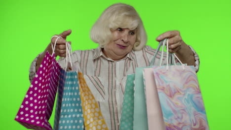 grandmother holding shopping bags, rejoicing discounts in store, enjoying shopping with low prices