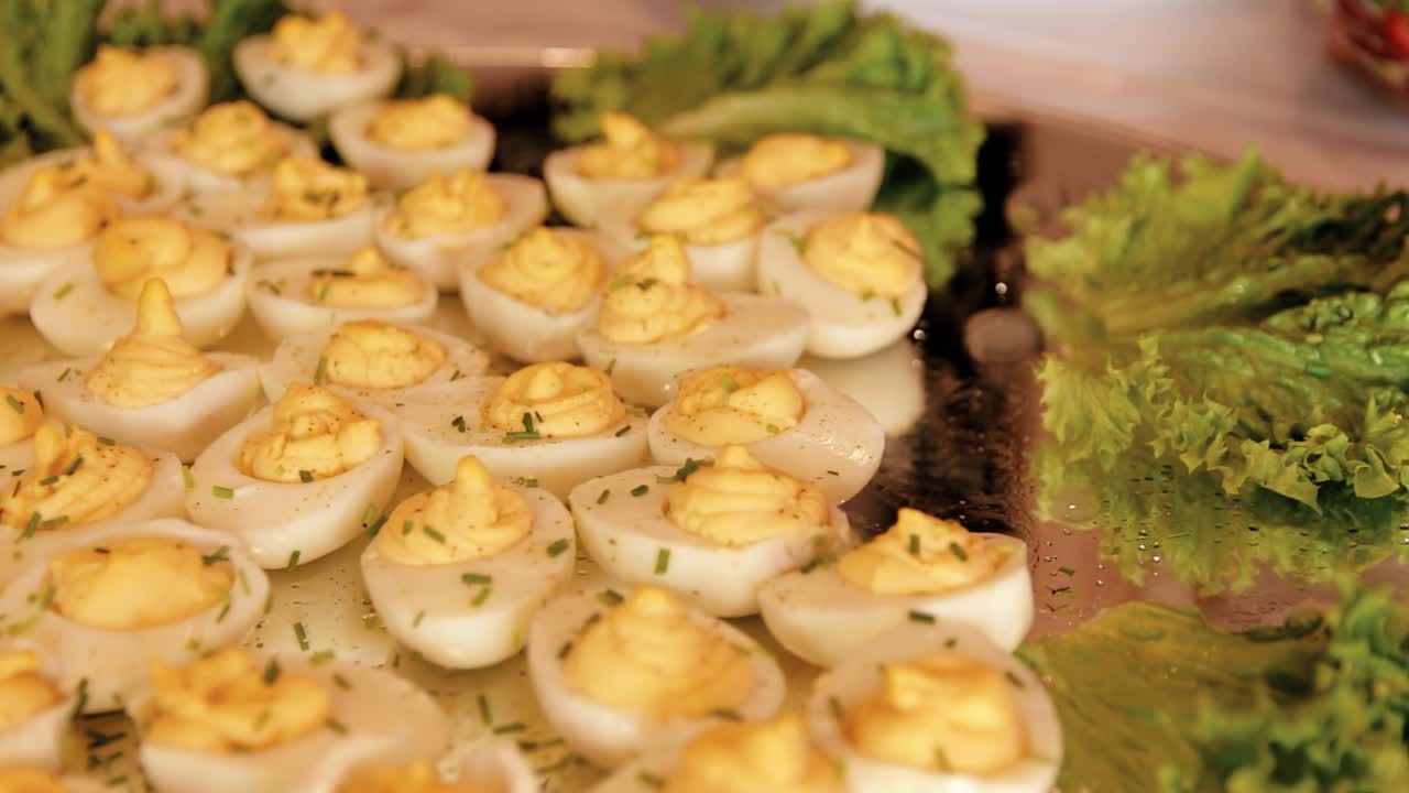 한 젊은 여성이 셀프 서비스 테이블에서 계란 크림으로 채워진 계란 흰자를 가져옵니다.