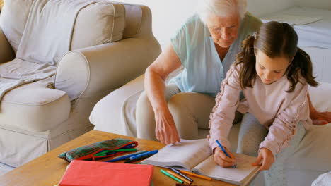 Front-view-of-Old-Caucasian-grandmother-helping-her-granddaughter-with-homework-at-home-4k