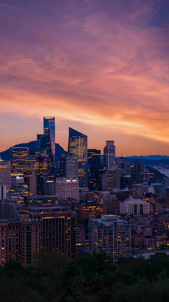 Vertical video: Sunset deepening, city skyline lighting from hillside lookout, glass towers shining