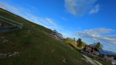 las imágenes de fpv se filmaron en el pueblo de montaña esloveno en los alpes con un dron volando rápidamente sobre las montañas filmadas con una gopro con paisajes circundantes volando entre y sobre pequeñas cabañas de madera