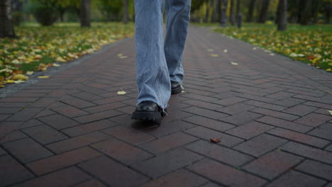 Close-up-unknown-female-walking-in-boots-and-jeans-in-autumn-park.-Relax-time