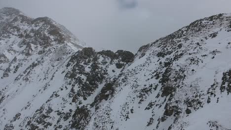 A-high-flying,-4K-drone-shot-over-an-extreme,-snowy-mountain-ridge,-known-as-the-"East-Wall",-that-looms-over-Arapahoe-Basin-Ski-Resort,-in-the-Rocky-Mountains-of-Colorado,-during-the-winter-season