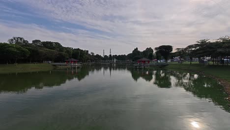 a tranquil lake in a tropical public park surrounded by lush greenery. visitors enjoy recreation and relaxation in this serene setting.