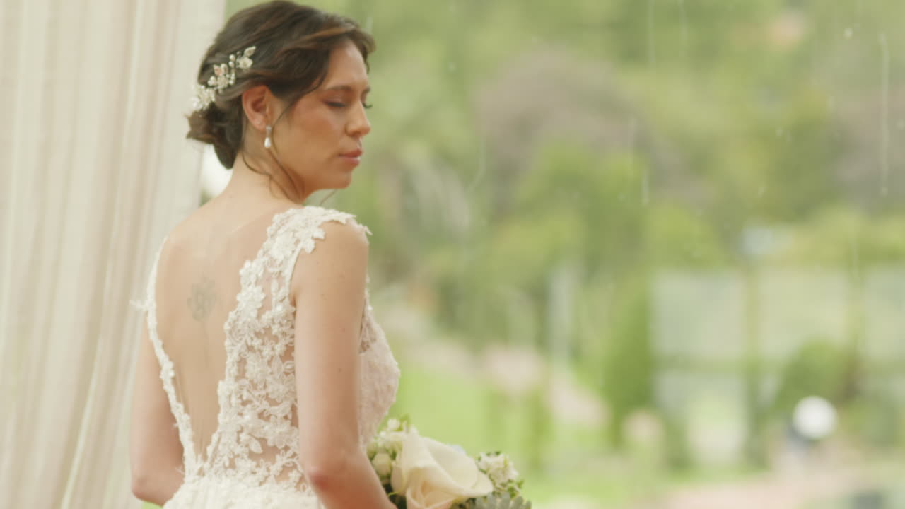 Medium shot of a bride walking with a bouquet of flowers, wearing a lace dress as she heads to the ceremony.