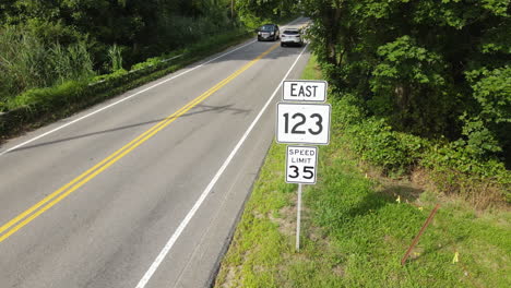 long aerial shot of cars passing road signs, loopable static shot