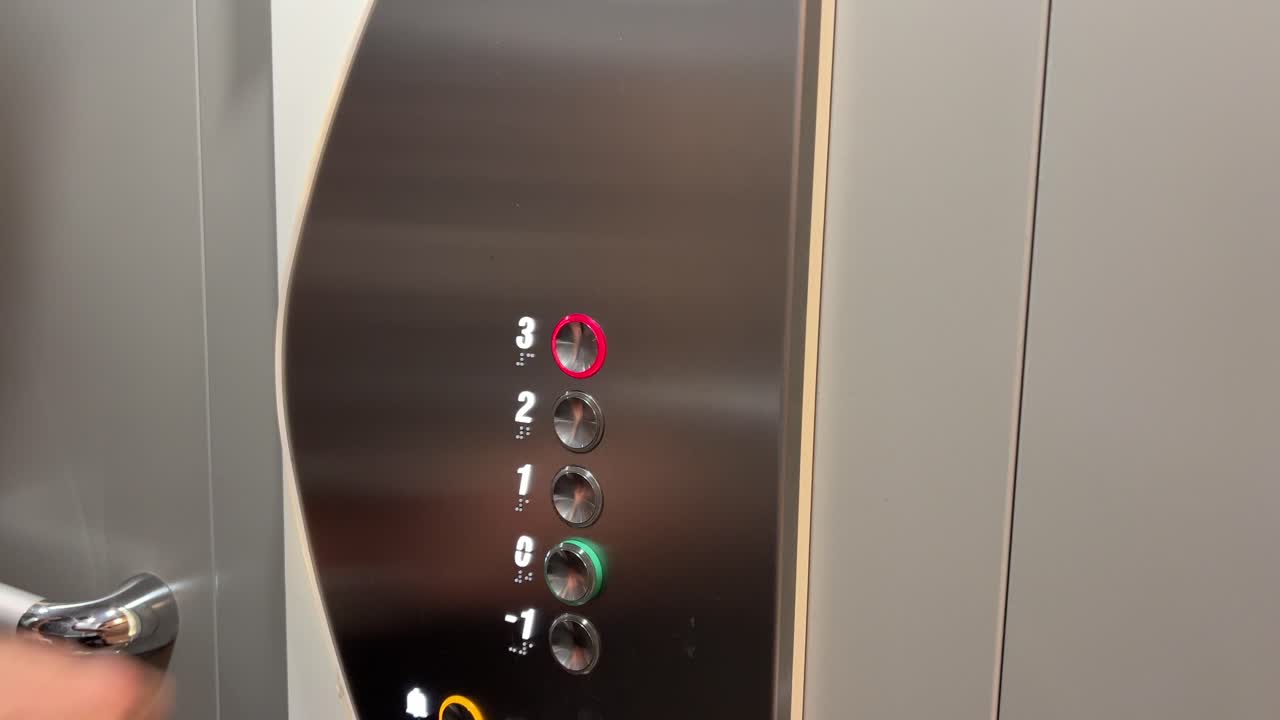 Male hand pressing button in a modern elevator, going up to third level