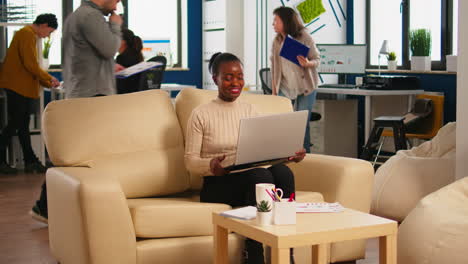 focused black manager reading tasks on laptop and typing sitting on couch