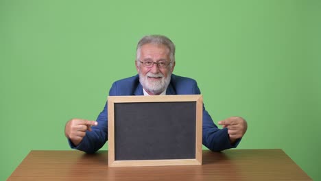 handsome senior bearded businessman against green background