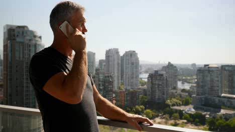 Man-talking-on-mobile-phone-in-balcony-4k