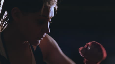 A-beautiful-woman-boxer-trains-in-a-dark-gym-and-works-out-punches-in-slow-motion.-side-view.-Steadicam-shot