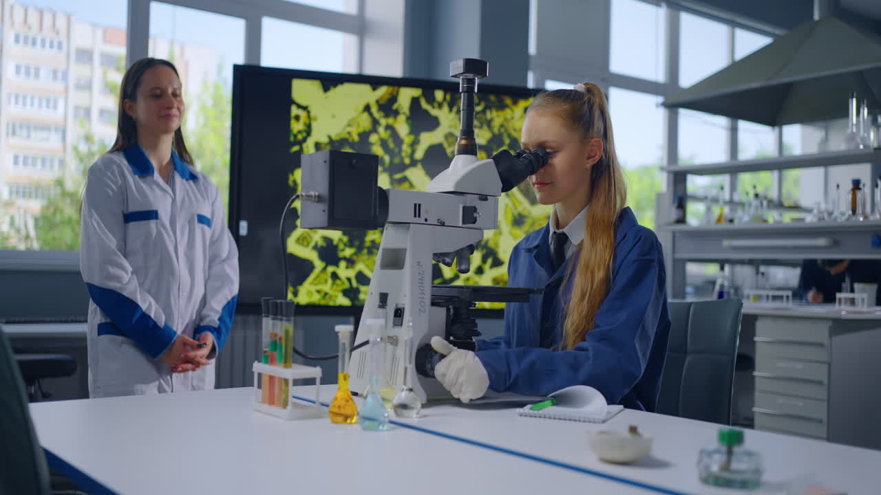 ученик наблюдает через микроскоп в научной лаборатории