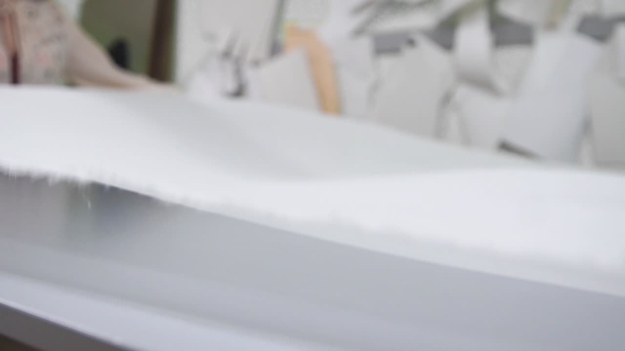 дизайнер одежды работает с измерениями на студийном столе. снято в 4k uhd . крупный план развернуть шнур из белой ткани в белом и светло-цветном шитье в замедленном движении.