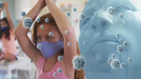 Animation-of-model-head-with-covid-19-cells-and-schoolgirl-in-classroom-wearing-face-masks